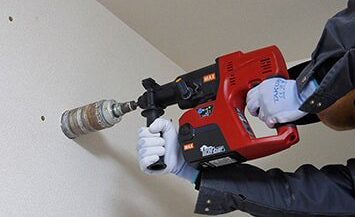 コアドリルで木造の壁に穴をあける様子